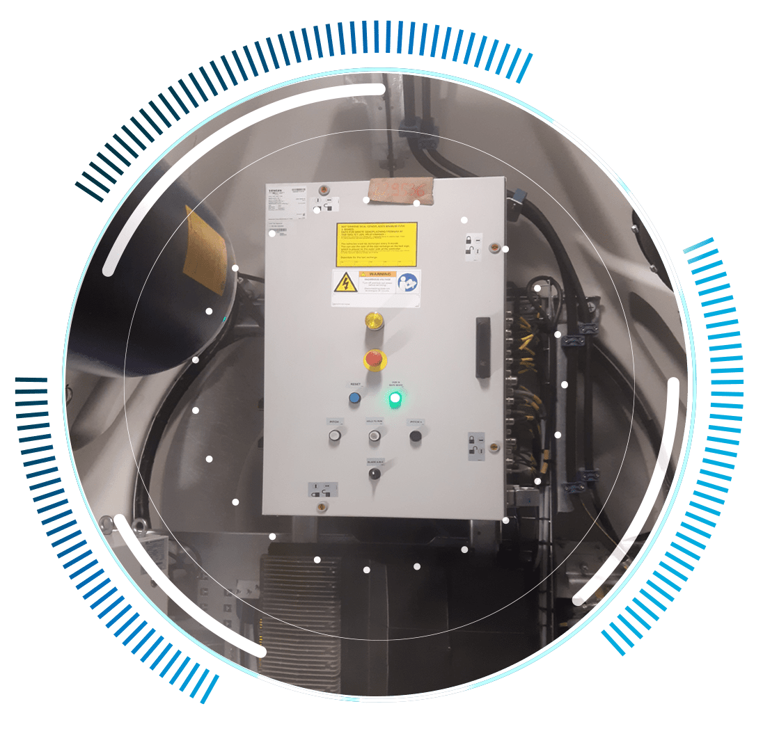 skywings.com.pl - A white industrial control panel with warning labels, buttons, and indicator lights is mounted on a wall, surrounded by blue and white circular graphic elements—ideal for wind turbine hydraulic system service needs. Wind Turbine Service & Maintenance, Windenergieanlagen-Service & Instandhaltung