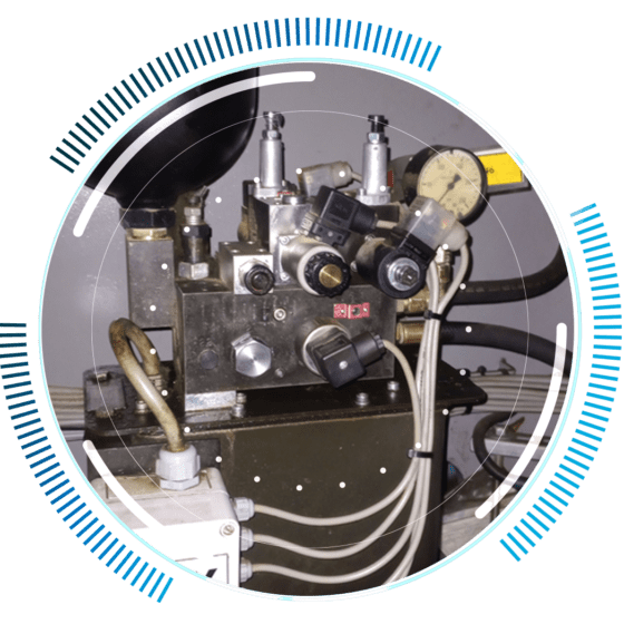 skywings.com.pl - A close-up of industrial machinery with various valves, gauges, wires, and connectors—ideal for illustrating wind turbine gearbox repair—framed by a circular blue and white graphic overlay. Wind Turbine Service & Maintenance, Windenergieanlagen-Service & Instandhaltung