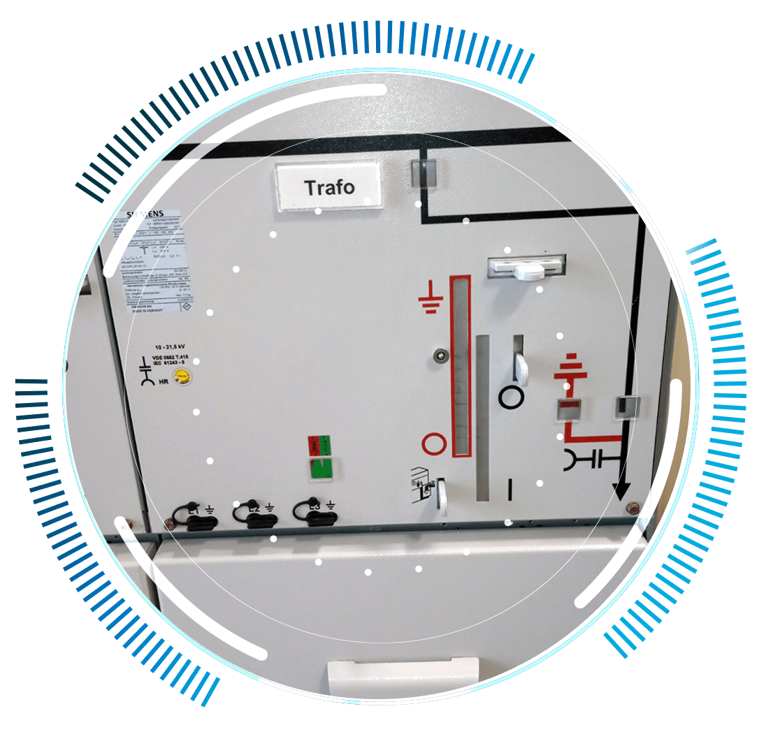 skywings.com.pl - A grey electrical control panel labelled Trafo with various switches, indicator lights, diagrams, and signs—essential for wind turbine drivetrain maintenance—framed by a circular blue and white graphic overlay. Wind Turbine Service & Maintenance, Windenergieanlagen-Service & Instandhaltung